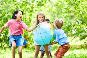 Glückliche Kinder draußen beim Spielen mit einem großen, aufblasbarem Globus.