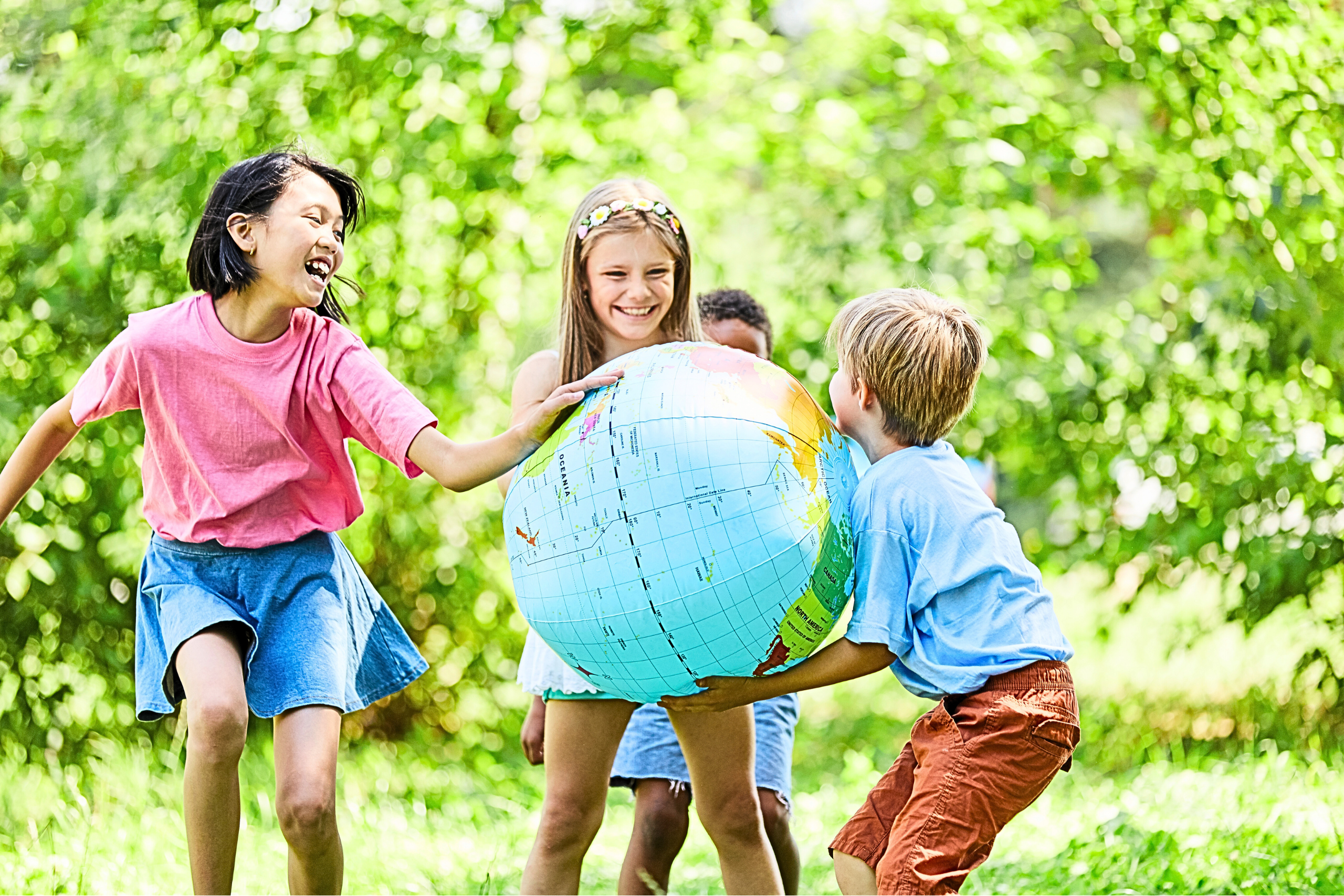 Glückliche Kinder draußen beim Spielen mit einem großen, aufblasbarem Globus.