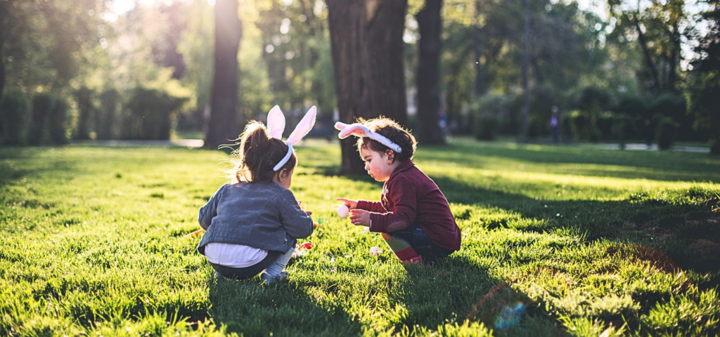 Kinder die auf einer Wiese zu Ostern Eier suchen