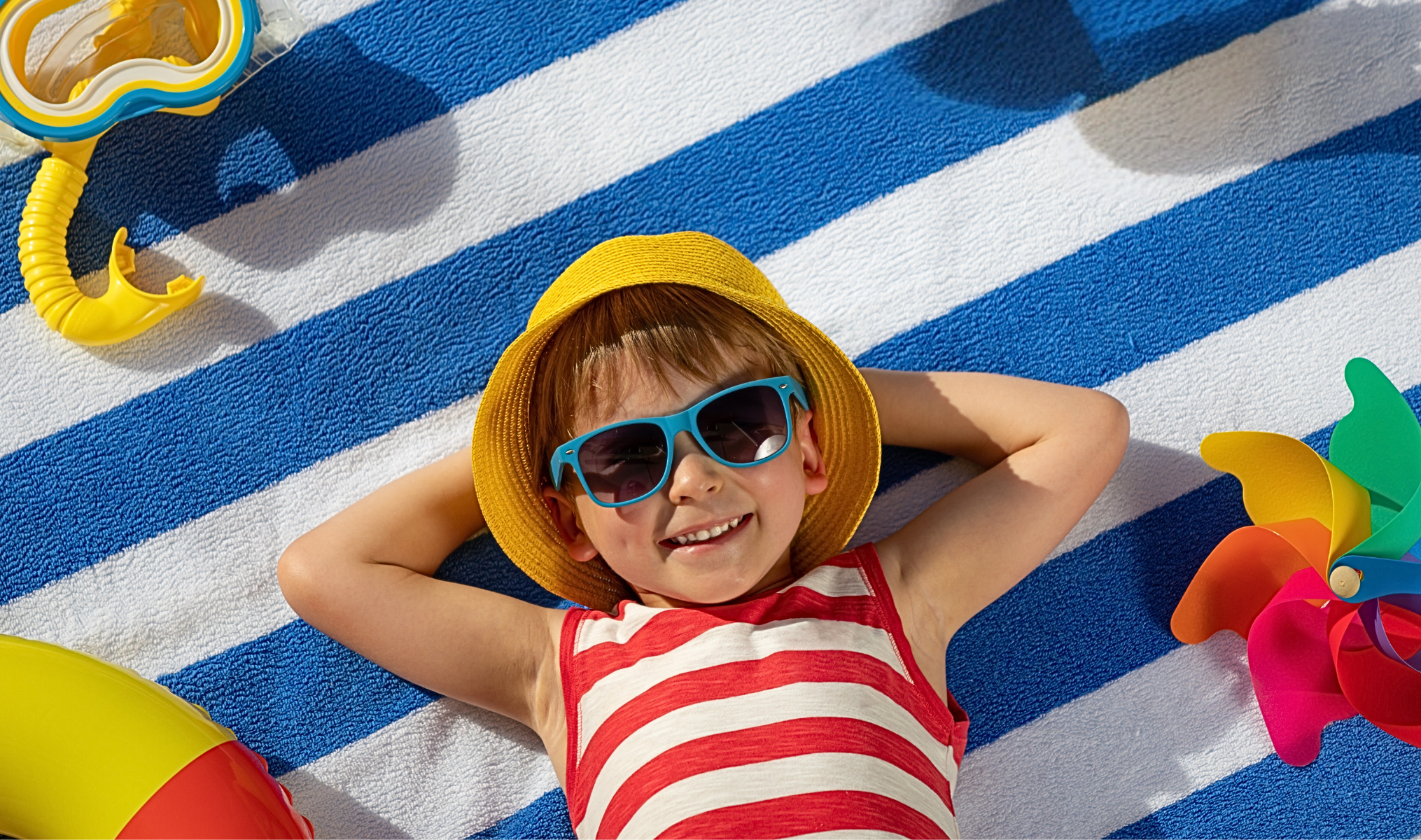Glückliches Kind liegt auf Badetuch und genießt Sommer und Sonne.