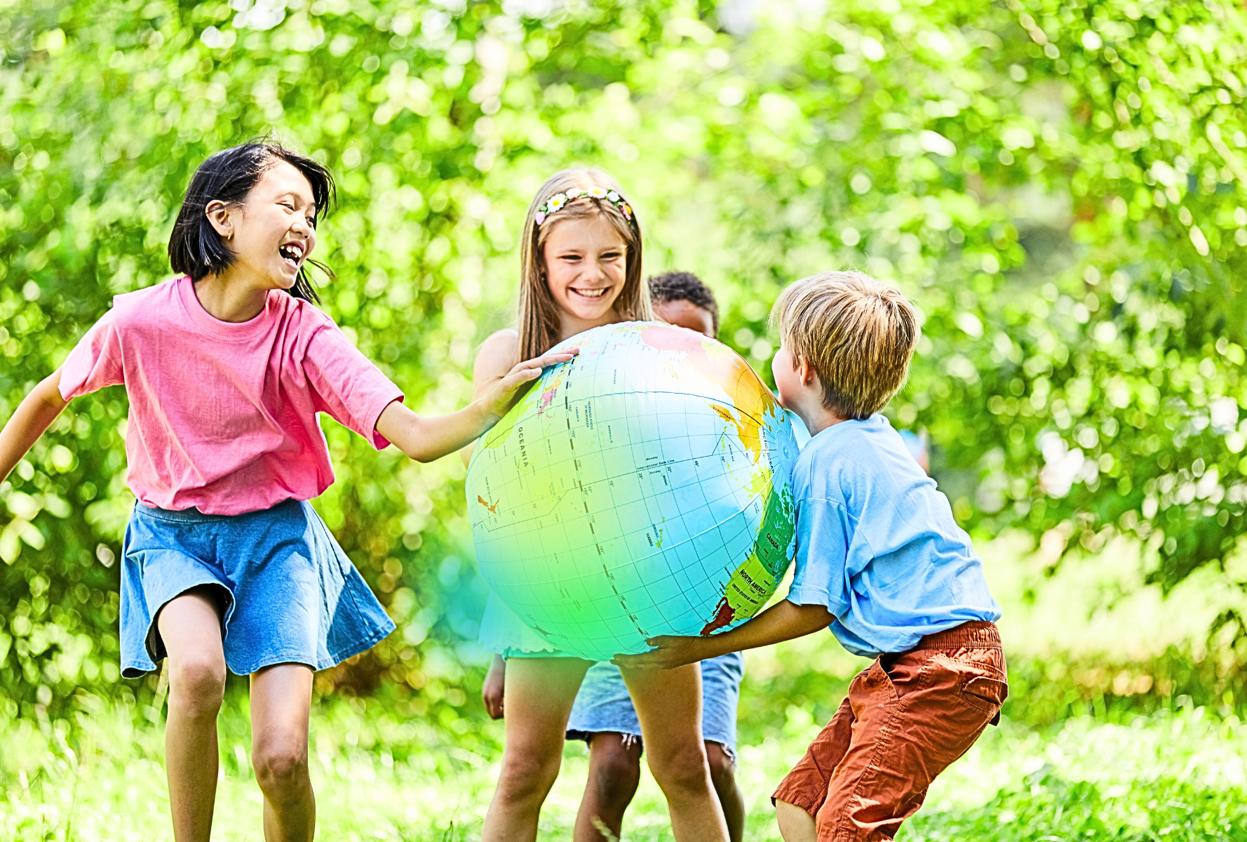 Glückliche Kinder draußen beim Spielen mit einem großen, aufblasbarem Globus. Sie entdecken die Welt und Energiegemeinschaften.