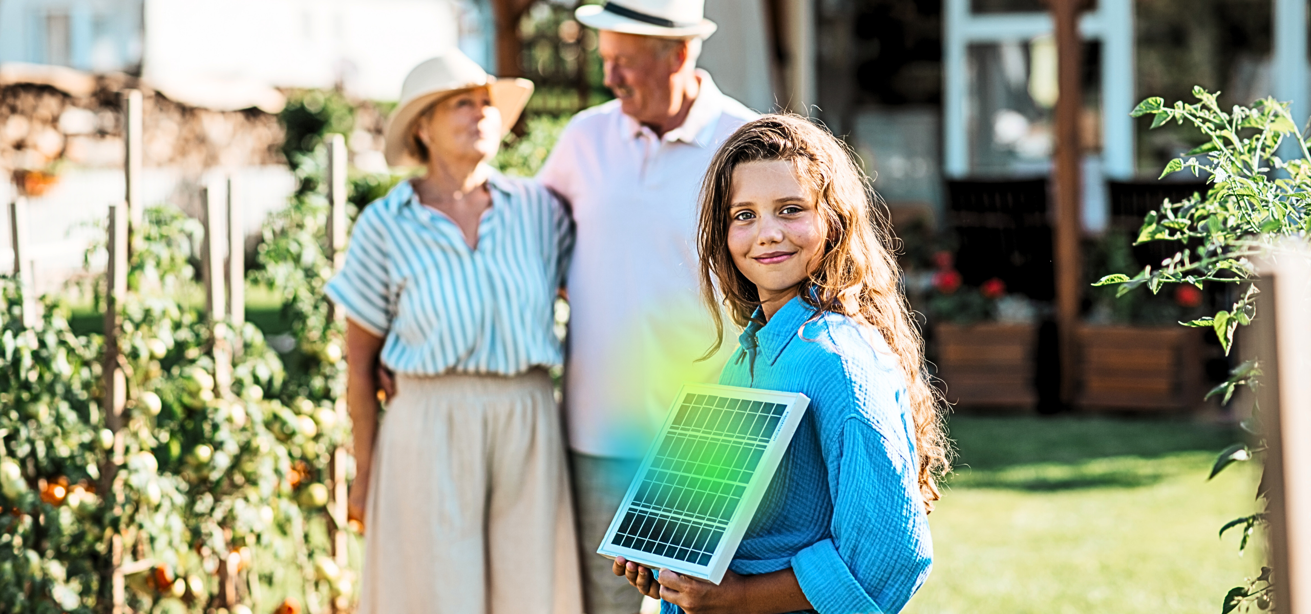 Glückliches Kind mit kleinem PV-Modul in der Hand, steht im Garten vor seinen Großeltern und betreibt Energy Sharing.